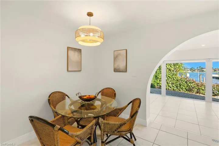 Dining room featuring light tile patterned floors, a water view, and arched walkways
