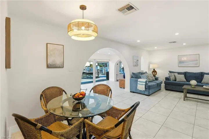 Dining space featuring arched walkways, recessed lighting, and light tile patterned floors