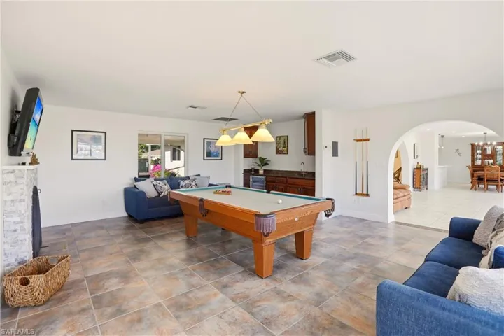 Recreation room with pool table, arched walkways, a fireplace, and wine cooler