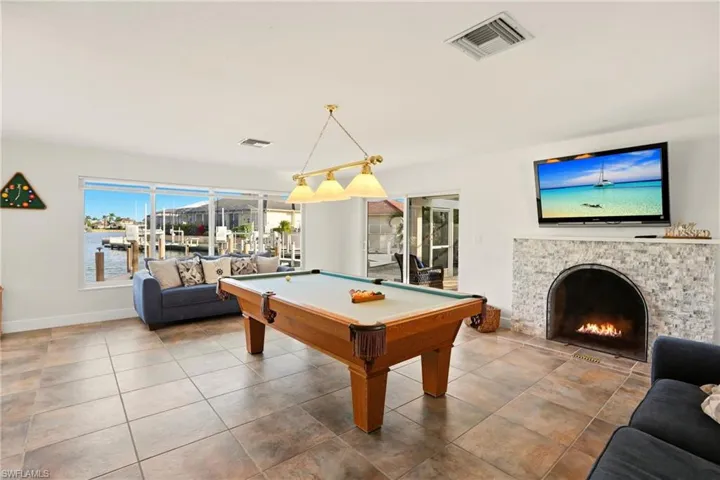 Playroom featuring a warm lit fireplace, pool table, and tile patterned flooring
