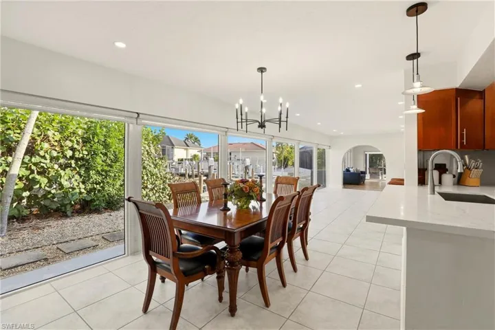 Dining space with light tile patterned floors, recessed lighting, arched walkways, and a chandelier