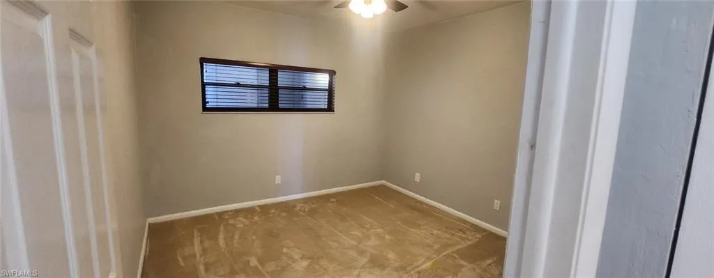 Carpeted spare room featuring ceiling fan