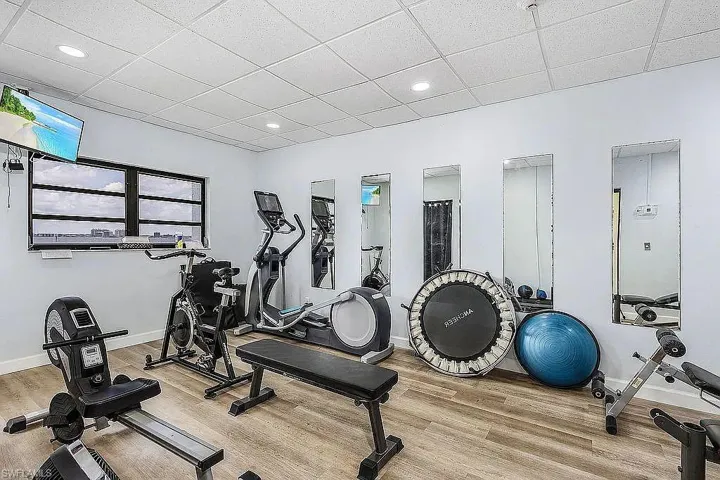 Exercise room with light hardwood / wood-style flooring and a paneled ceiling