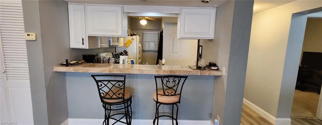 Kitchen with white cabinets, ceiling fan, a kitchen bar, and light hardwood / wood-style flooring