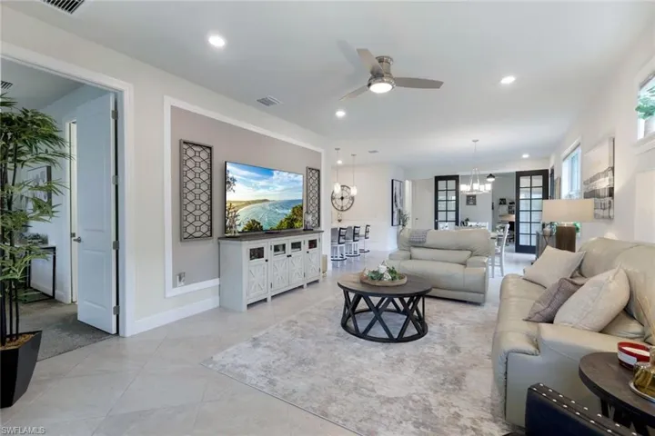 Living room featuring ceiling fan with notable chandelier