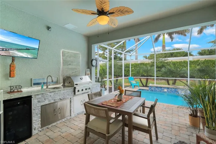 View of patio / terrace featuring grilling area, an outdoor kitchen, sink, glass enclosure, and ceiling fan