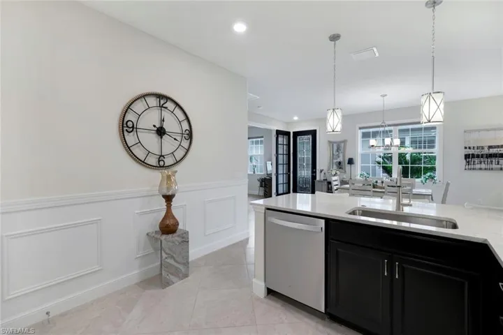 Kitchen featuring light tile patterned flooring, sink, a chandelier, pendant lighting, and dishwasher