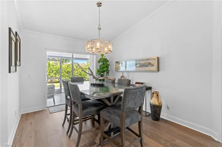 Dining space with ornamental molding, wood finished floors, and vaulted ceiling