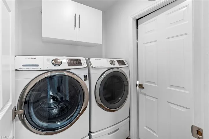 Washroom featuring cabinet space and washing machine and clothes dryer