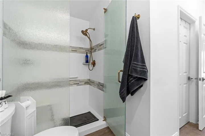 Full bath with a shower stall and wood finished floors