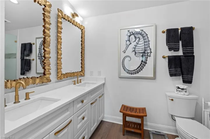Bathroom with double vanity and dark wood-type flooring