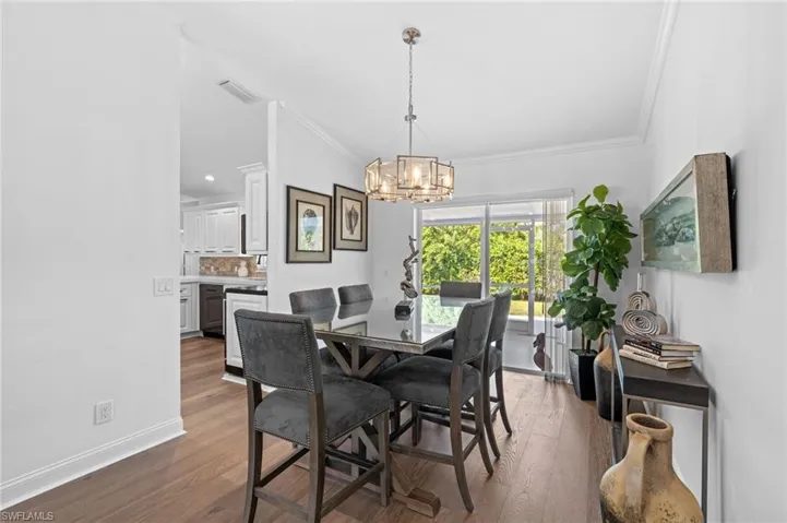 Dining room featuring dark wood-style flooring, ornamental molding, and a chandelier