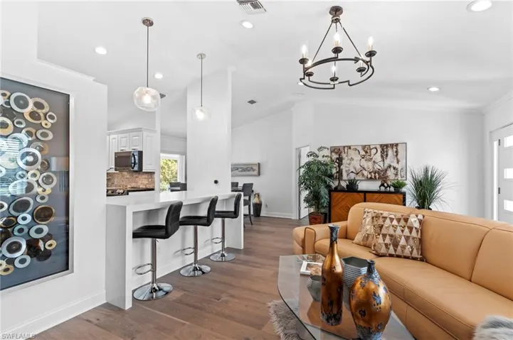 Living room featuring dark wood finished floors, recessed lighting, lofted ceiling, and a chandelier