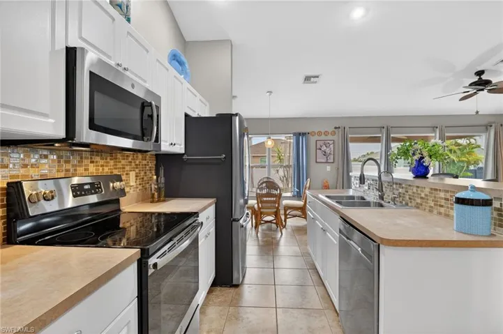 Kitchen featuring stainless steel appliances, backsplash, light countertops, white cabinets, and recessed lighting