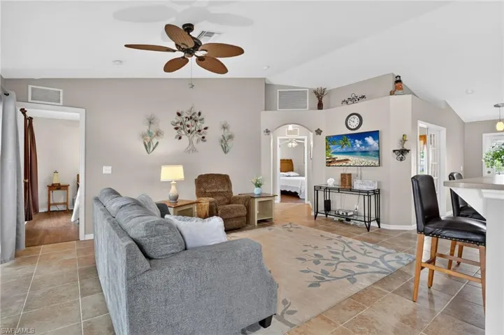 Living area with a ceiling fan, split bedroom floor plan, lofted ceiling, and tile patterned flooring