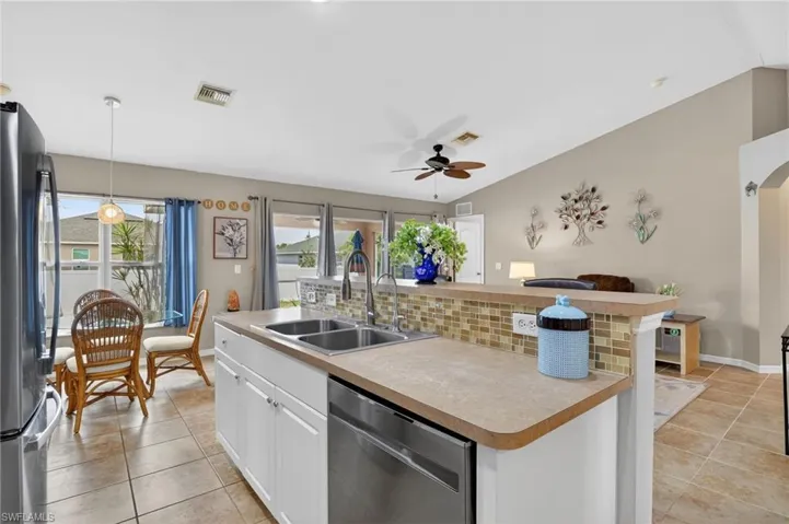 Kitchen with a kitchen island with sink, lofted ceiling, open floor plan.