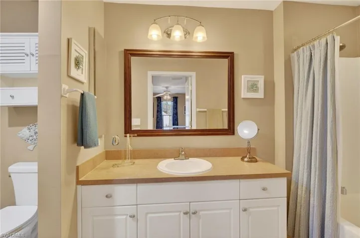 Primary ensuite featuring privacy wall for toilet, vanity and shower / bath combo