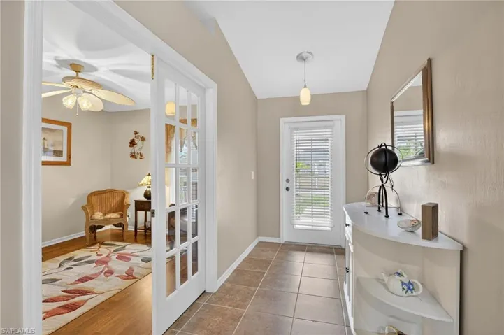Welcoming entry foyer with tile patterned floors, French doors to den.