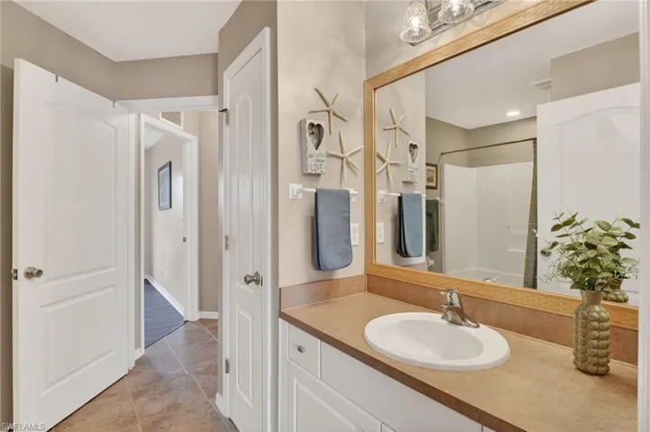 Full bath featuring vanity, tile patterned floors, and tub / shower combo, w/ 2 doors for easy access from hallway and second bedroom.