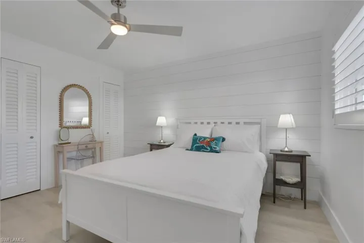Bedroom featuring multiple closets, a ceiling fan, wood walls, and light wood-style floors