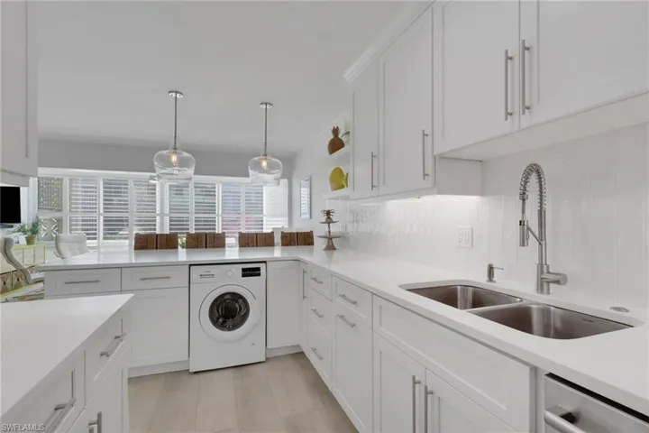 Kitchen featuring white cabinets, washer / clothes dryer, open shelves, and pendant lighting