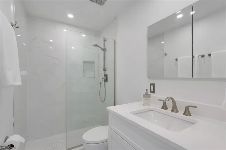 Bathroom with vanity and a marble finish shower