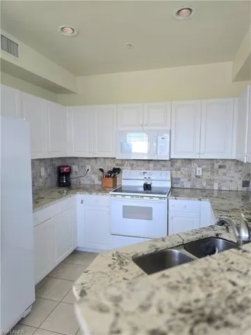 Ample cabinet space with granite countertops and stone backsplash