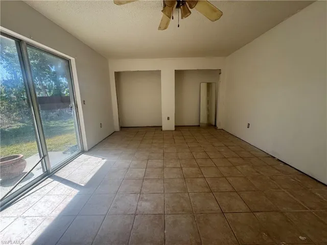 Unfurnished bedroom with ceiling fan, two closets, a textured ceiling, and access to exterior