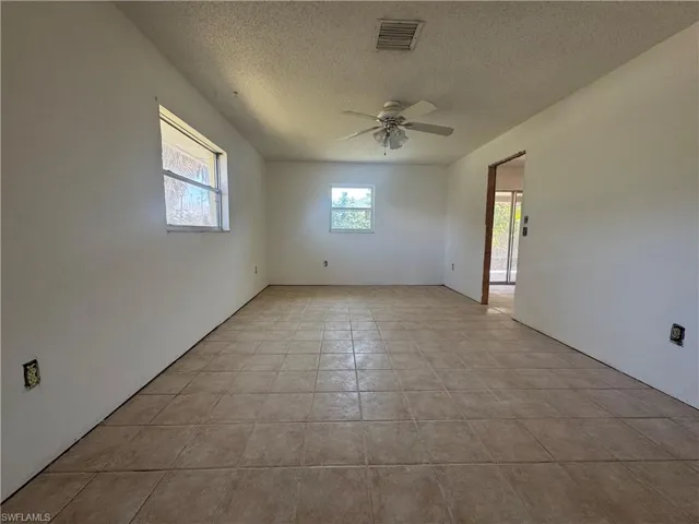 Spare room featuring a ceiling fan, a textured ceiling, and plenty of natural light