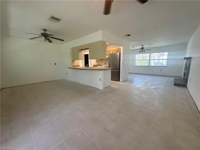 Unfurnished living room with a ceiling fan and light tile patterned floors