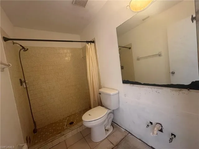 Bathroom with a shower stall and light tile patterned floors