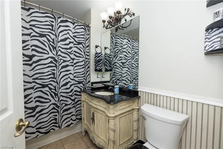 Bathroom with wainscoting, vanity, curtained shower, and light tile patterned floors