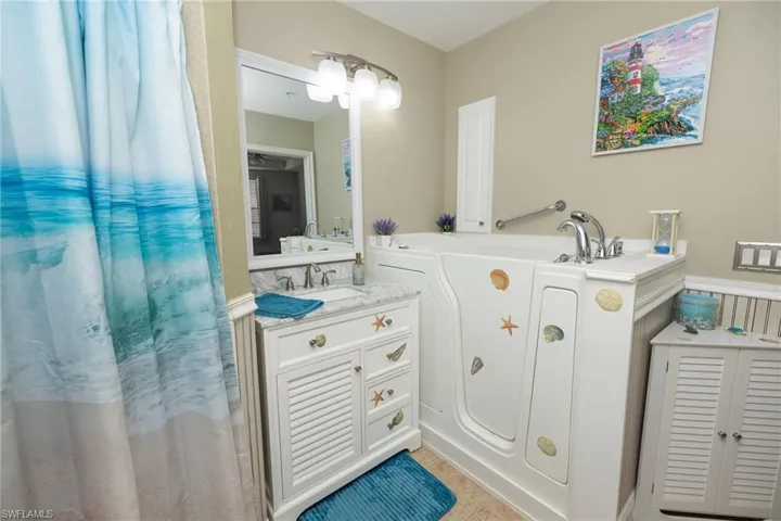 Full bath featuring vanity, a garden tub, and light tile patterned floors