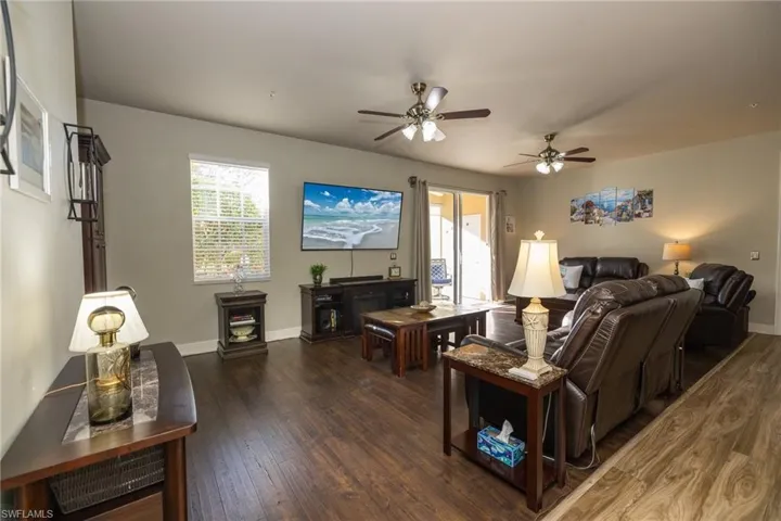 Living room with dark wood finished floors, ceiling fan, and plenty of natural light