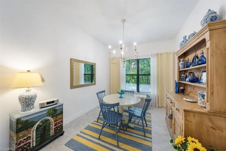 Dining space with light colored carpet, lofted ceiling, and a notable chandelier