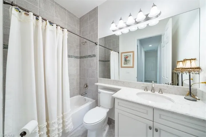 Full bathroom featuring shower / bath combo with shower curtain, tile patterned flooring, vanity, and toilet