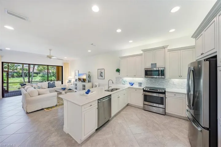 Kitchen featuring stainless steel appliances, sink, kitchen peninsula, light stone countertops, and ceiling fan