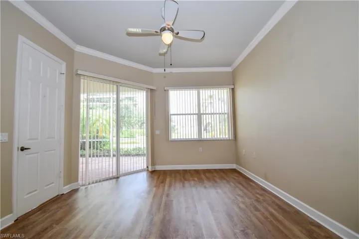 Empty room with crown molding, dark hardwood / wood-style floors, and ceiling fan