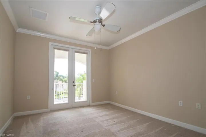 Empty room with ornamental molding, light colored carpet, and ceiling fan