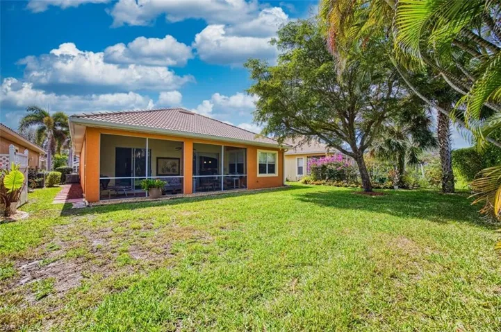Rear view of property with a yard, stucco siding, a sunroom, and a tiled roof