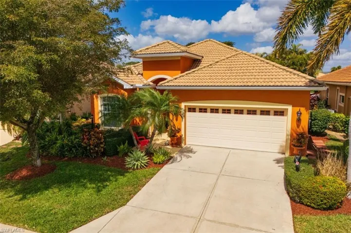 View of front of home with a garage, driveway, stucco siding, a tile roof, and a front lawn