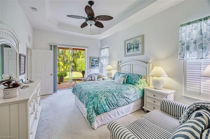 Bedroom with access to exterior, light carpet, ornamental molding, ceiling fan, and a raised ceiling