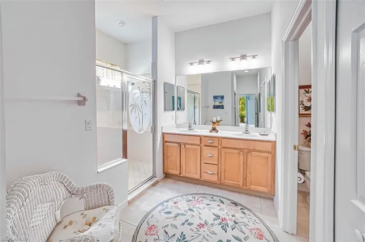 Full bathroom featuring double vanity, a shower stall, and light tile patterned floors