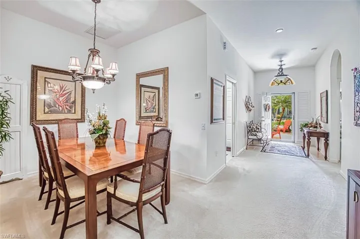 Dining area featuring light colored carpet, suspended lighting, and arched walkways