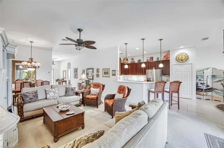 Living room with arched walkways, suspended lighting, light colored carpet, and ceiling fan