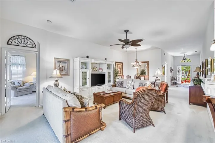 Living room with light carpet, a ceiling fan, and hanging lights