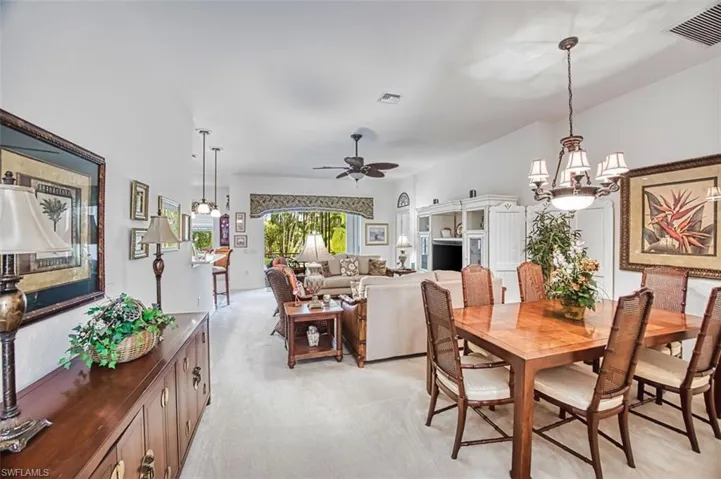 Dining area featuring ceiling fan, light carpet, and hanging lights