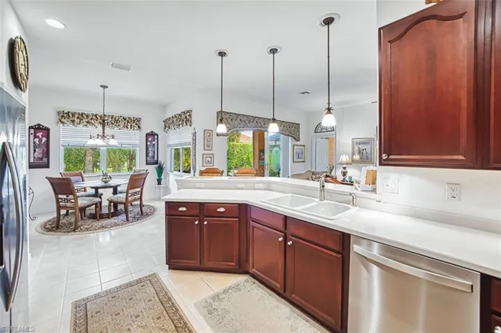 Kitchen with reddish brown cabinets, light countertops, stainless steel appliances, and a peninsula