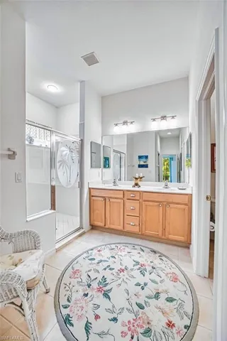 Bathroom featuring a stall shower, double vanity, and light tile patterned flooring
