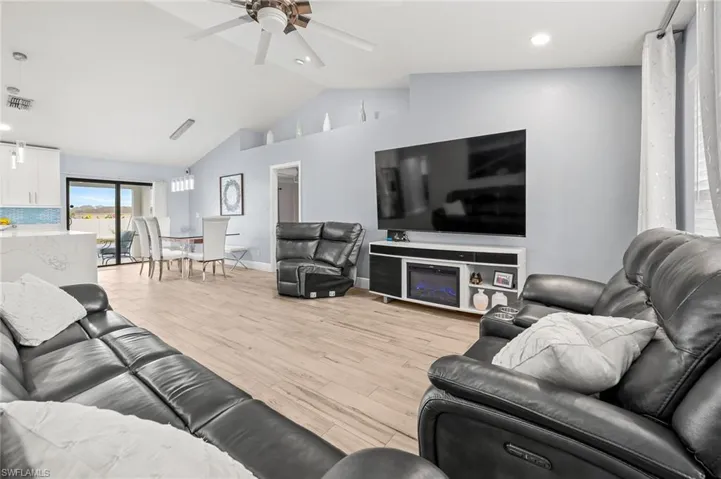 Living room with light wood finished floors, ceiling fan, recessed lighting, and a high ceiling